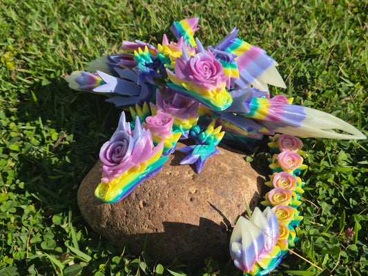Colorful dragon-shaped sculpture with floral details on a rock in grass